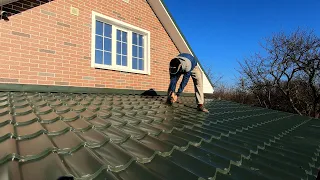 The guy is building an awesome pitched roof. Installation of metal tiles