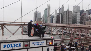 guy wearing 2 hats at the same time climbs the brooklyn bridge
