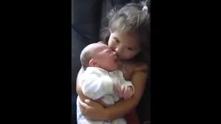 Big sister preciously holds newborn baby brother