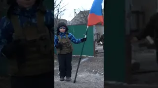 В Троицком (ЛНР) мальчик в шлеме танкиста встречает колонну российских военных с триколором в руках.