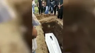 Grave concern! Haunting moment corpse appears to WAVE to mourners through coffin's glass panel