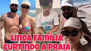 Andressa Suita e Gusttavo Lima andam juntinhos pela praia enquanto as crianças brincam na areia