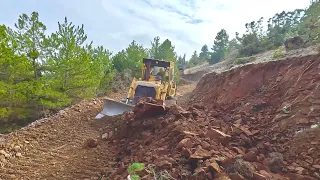 Bulldozer pushes material off the road that the excavator removed from the hillside #caterpillar