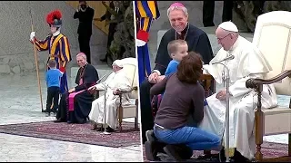 Pope chuckles as small mute boy tugs on Swiss guard sleeve during audience