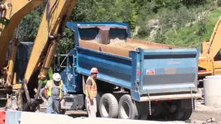 Blue Kenworth Dump Truck dumping dirt on a road construction site