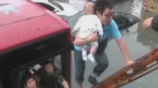 A baby is rescued from a trapped bus on a flooded road in east China