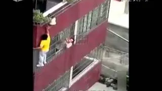 Toddler dangles by head from balcony.