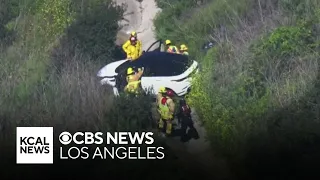 First responders work to rescue a woman inside a vehicle that went down a Newport Beach hillside