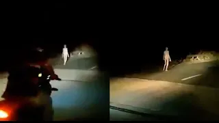 Creepy 'alien' figure with long limbs and pale skin walks along bridge at dead of night