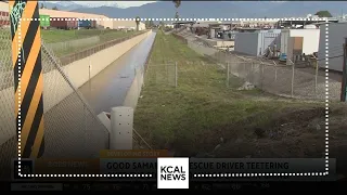 Good Samaritans help pull a vehicle to safety after teetering over a Chino drainage canal