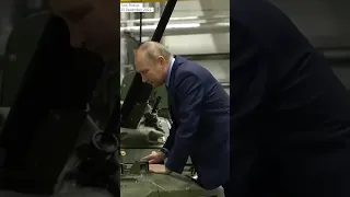 Putin walking up steps to take a closer look at armored vehicle as he tours arms production plant