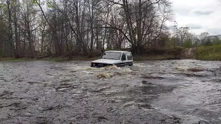 Lifted Toyota Land Cruiser J70 crossing wild river.