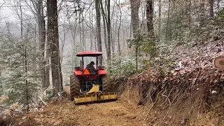 More Kubota M6060 digging a road in a steep hillside!