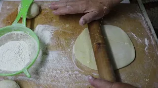 A person is slicing dough on a wooden cutting board for a recipe