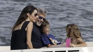 On a boat ride on Lake Como, George Clooney cuddles with wife Amal and twins Ella and Alexander,...