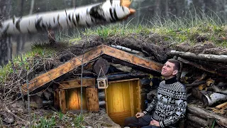 A DUGOUT in THE FOREST. STORMY WIND BREAKS TREES. REPAIRING THE OVEN