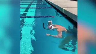 Swimmer swims with a glass of chocolate milk balanced on her head