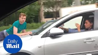 Bizarre moment man clings to woman's car bonnet as she drives away