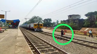 A Desparate man ignores local train and crossed rail line in front of train.