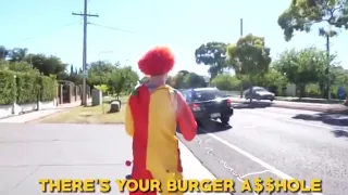 Clown throwing a burger at a car on the road