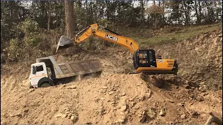 JCB Excavator Loading Soil On A Dump Truck in The Hilly Road Construction