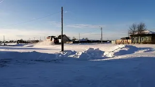 Два Камаз чистят снег на деревне. Дикая природа Сибири
