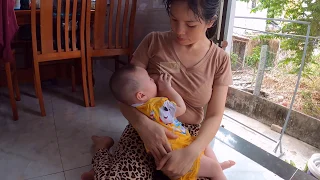 Mom Thuy is breastfeeding at home as daily routine for baby while she is doing cooking...