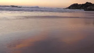 ENJOYING A STUNNING SUNSET IN A PEACEFULLY EMPTY BEACH OF CAPETOWN, SOUTH AFRICA