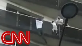 Man scales building to save dangling child