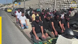 Muslims take part in Friday prayers as Israeli soldiers look on