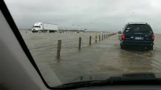 Cars drive through flooded highway