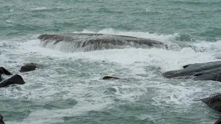 Marine water and giant waves crashing at rocky cliff with splashing and white foam