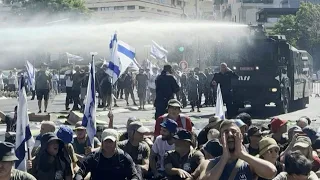 Israeli police use a water cannon to disperse protesters blocking road to parliament | AFP