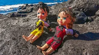 Elsa and Anna toddlers play with black sand on the beach