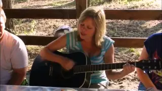 Девушка очень красиво играет на гитаре и поет песню