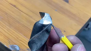 Sharpen a large drill bit by hand using a belt sander