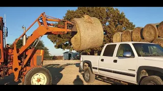 Loading and unloading a round bale of hay in the back of a truck