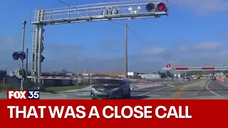 Driver appears to blow through crossing arm, barely missing train