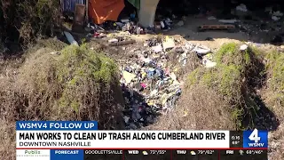 Man works to clean up trash, debris along river