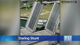 A man climbs his way to the top of an open draw-bridge