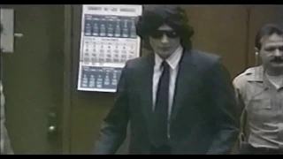 Richard Ramirez wearing a fancy suit in court + sticking tongue out. (no sound)