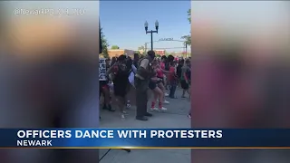 Police officers dance with protesters in Newark