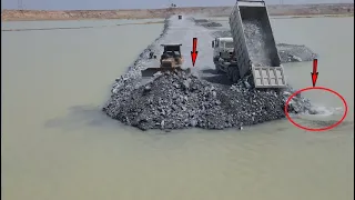Road in lake best action by bulldozer komatsu pushing big stone into water