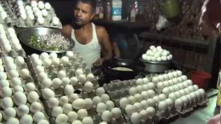 Man cooking Egg Omelette and giving it to customer on bread.