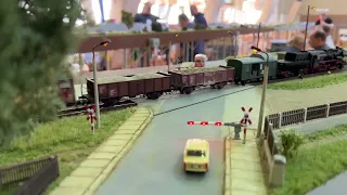 Dampflok überquert Bahnübergang mit Schranke