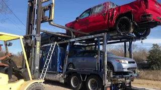 Car hauler unloading salvage cars with forklift