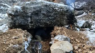 Building a shelter under a big rock in freezing weather