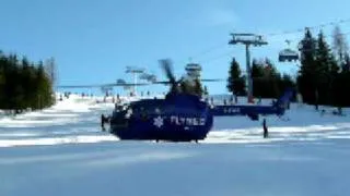 Rescue helicopter taking off from ski run