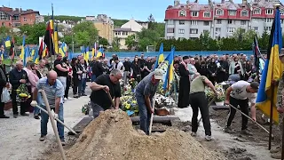 Присутні на похованні співають гімн України.