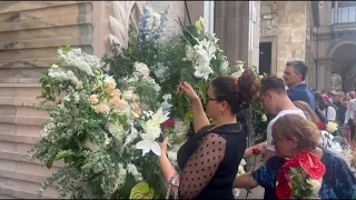 La folla davanti al Duomo porta via l'ultimo ricordo di Berlusconi: a ruba i fiori delle corone